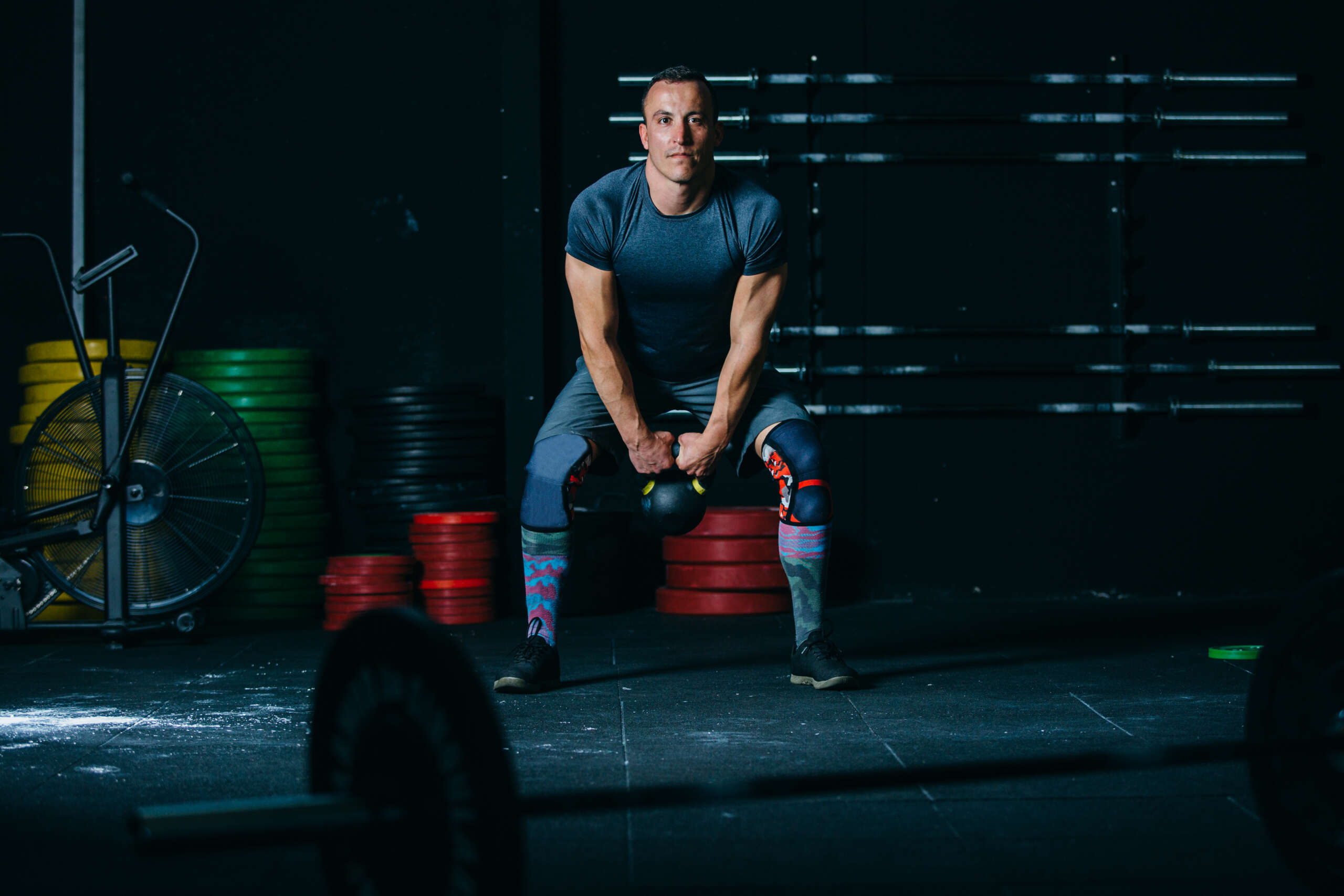 Front view of a young athlete man doing kettlebell swing exercise on a fitness routine at the box gym