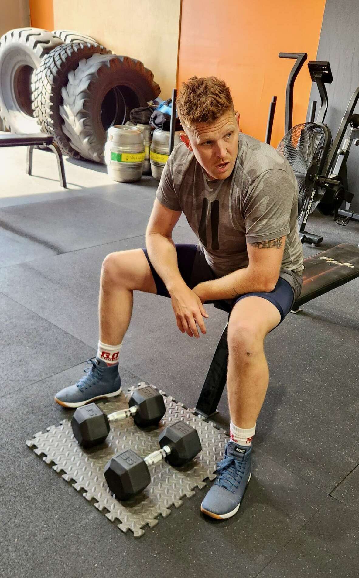 athletic man on dumb bell bench doing arm curls at gym in auburn wa